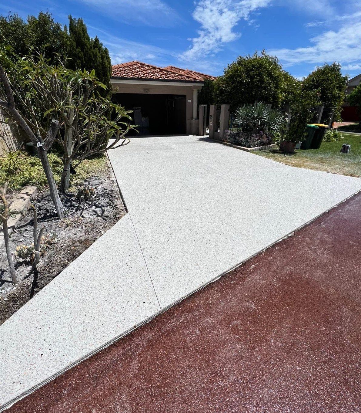 Exposed aggregate driveway beside a coloured concrete border band